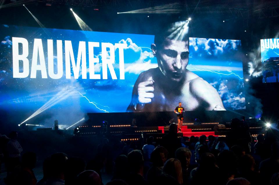 Max Baumert beim Einlauf in die Arena bei GLORY Kickboxing, auf der Leinwand groß sein Porträt